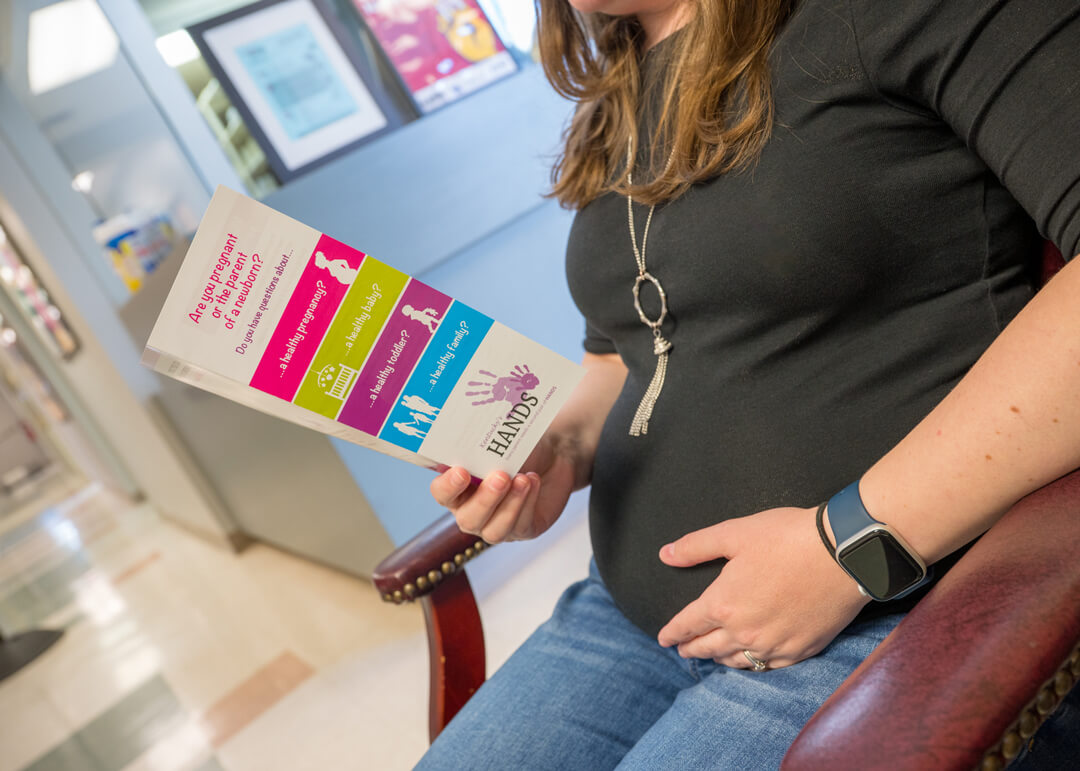 Pregnant woman reading a pamphlet in the lobby of a health department